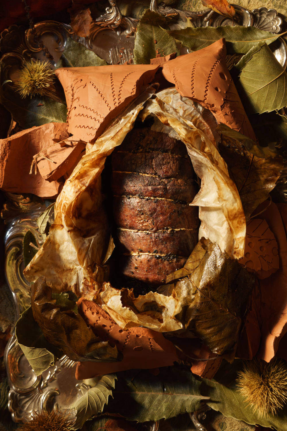 rôti de sanglier cuit en croûte d'argile dans des feuilles de châtaignier
